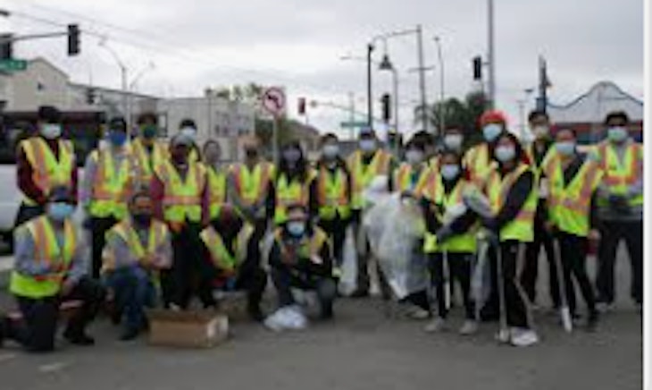 Large group of volunteers posing with neon safety vest and trash piles