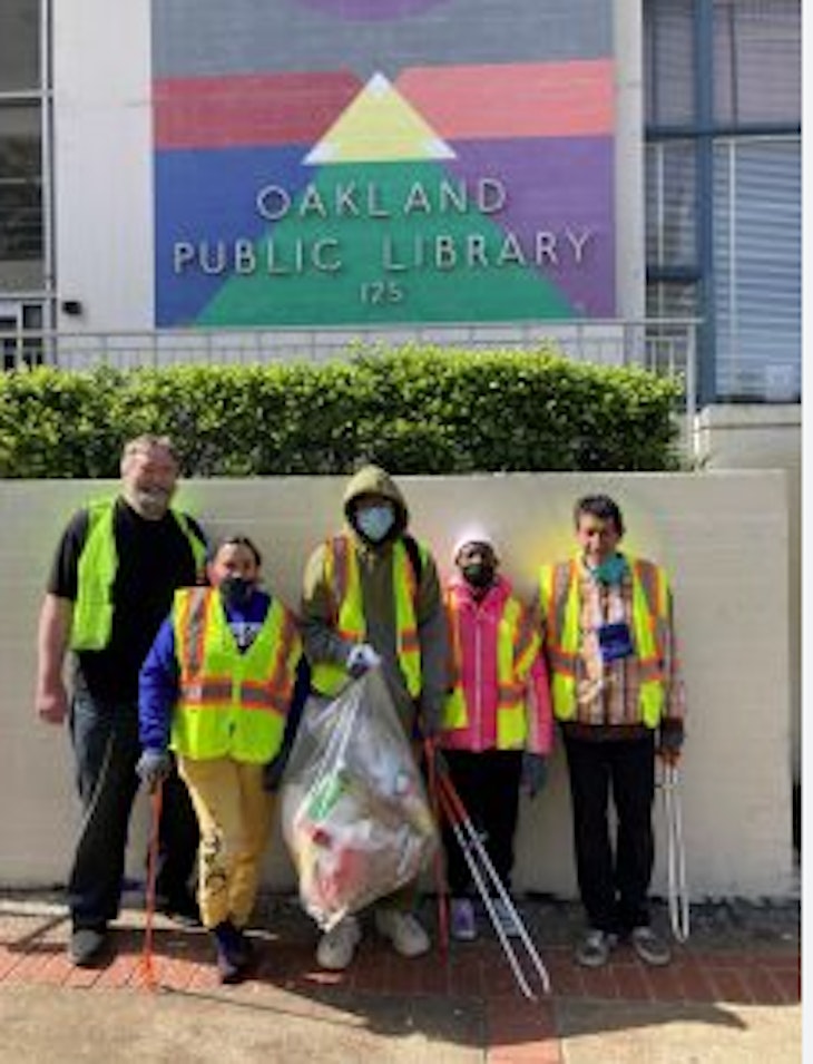 five enthusiastic volunteers with trash and pickers