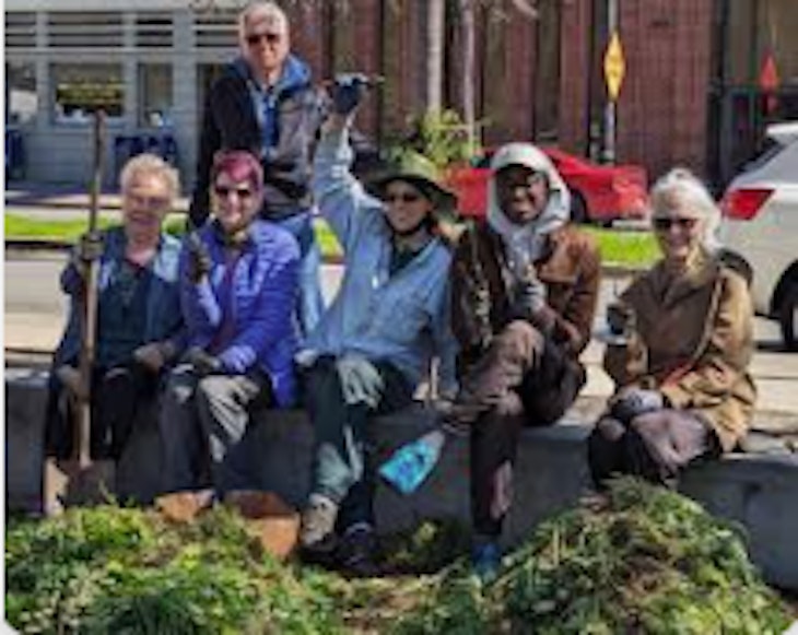 group of volunteers sitting with garden tools