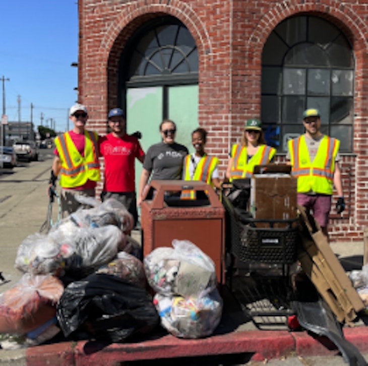 Group of volunteers with neon safety vest in front of trash and debris collected