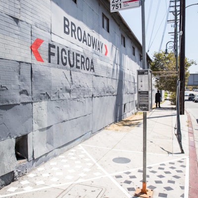 A painted wall shows wayfinding directions to Broadway and Figueroa on 26 Avenue in Los Angeles.