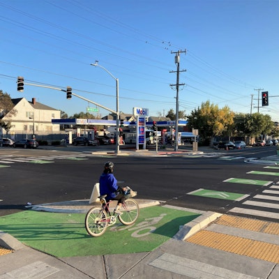 Cyclist in protected intersection at West Street and W MacArthur Boulevard