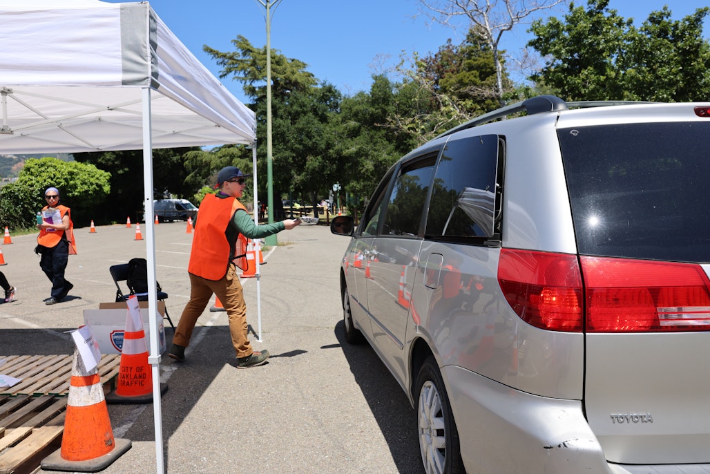 This is a photo of an Oakland CERT Volunteer distributing critical goods at a vehicular CPOD.