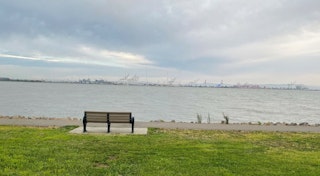 Empty bench with grass in foreground looking out over San Francisco Bay on cloudy day