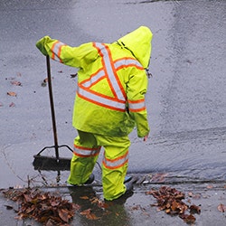 Photo of Person cleaning storm drain in rain